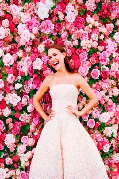 Смеющаяся невеста на фоне цветочной стены.